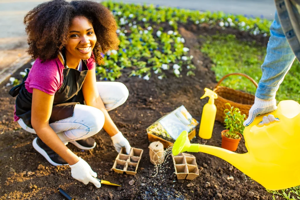 Young woman smiling while planting flowers in a Newark community garden as part of the Small Grants Program