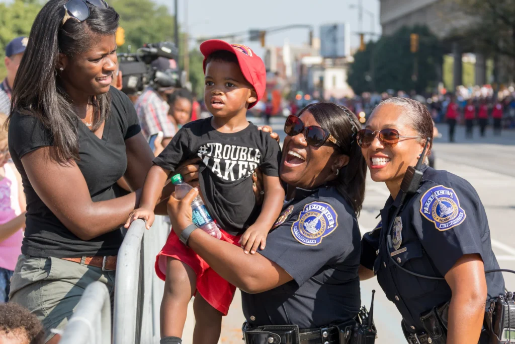 Police officers smiling and posing with a young child and mother at a National Night Out community event in Newark