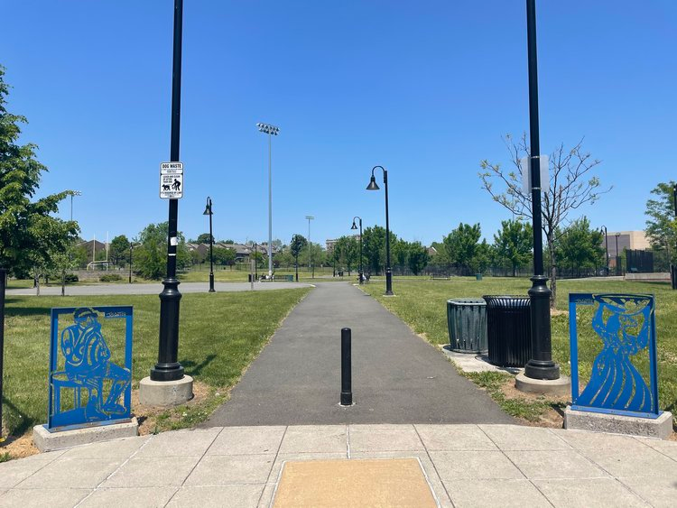 Two blue steel sculptures of a male Blues musician and a female Gospel singer, positioned near the side entrance of Nat Turner Park on Muhammad Ali Avenue.