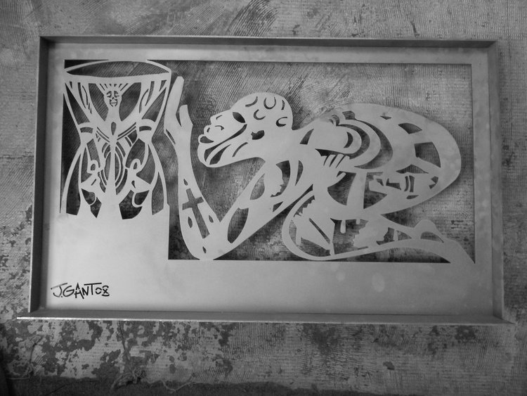 Steel cut-out model of a crouching sphinx figure by artist Jerry Gant, displayed on a textured surface.