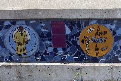 Two round mosaic tiles featuring a choir singer and musical terms, set in a blue tile background at Nat Turner Park