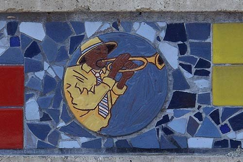 Round mosaic tile of a jazz musician playing trumpet, surrounded by blue and red tiles at Nat Turner Park in Newark, NJ