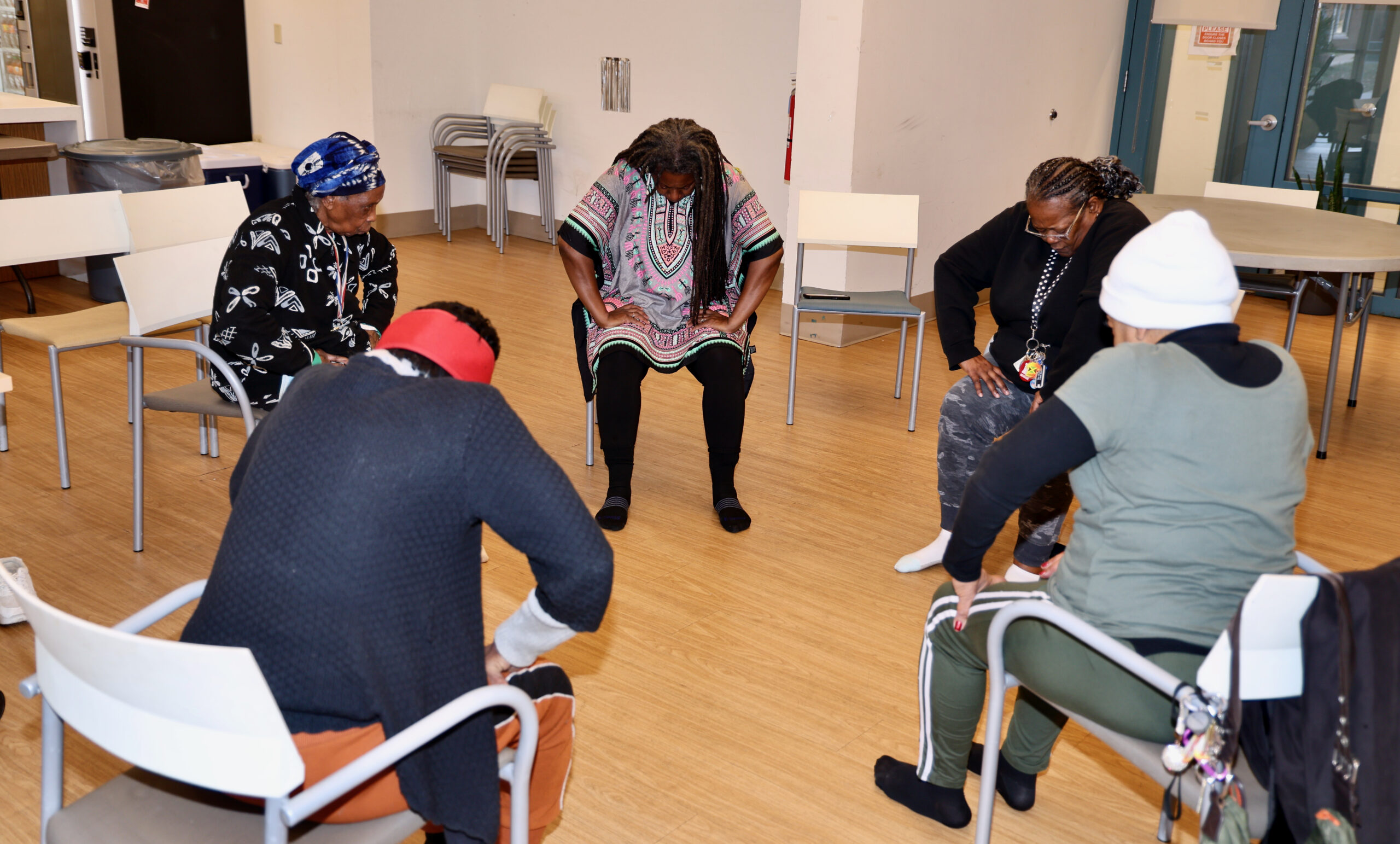 Seniors performing a seated forward stretch during a group yoga session at Grace Manor