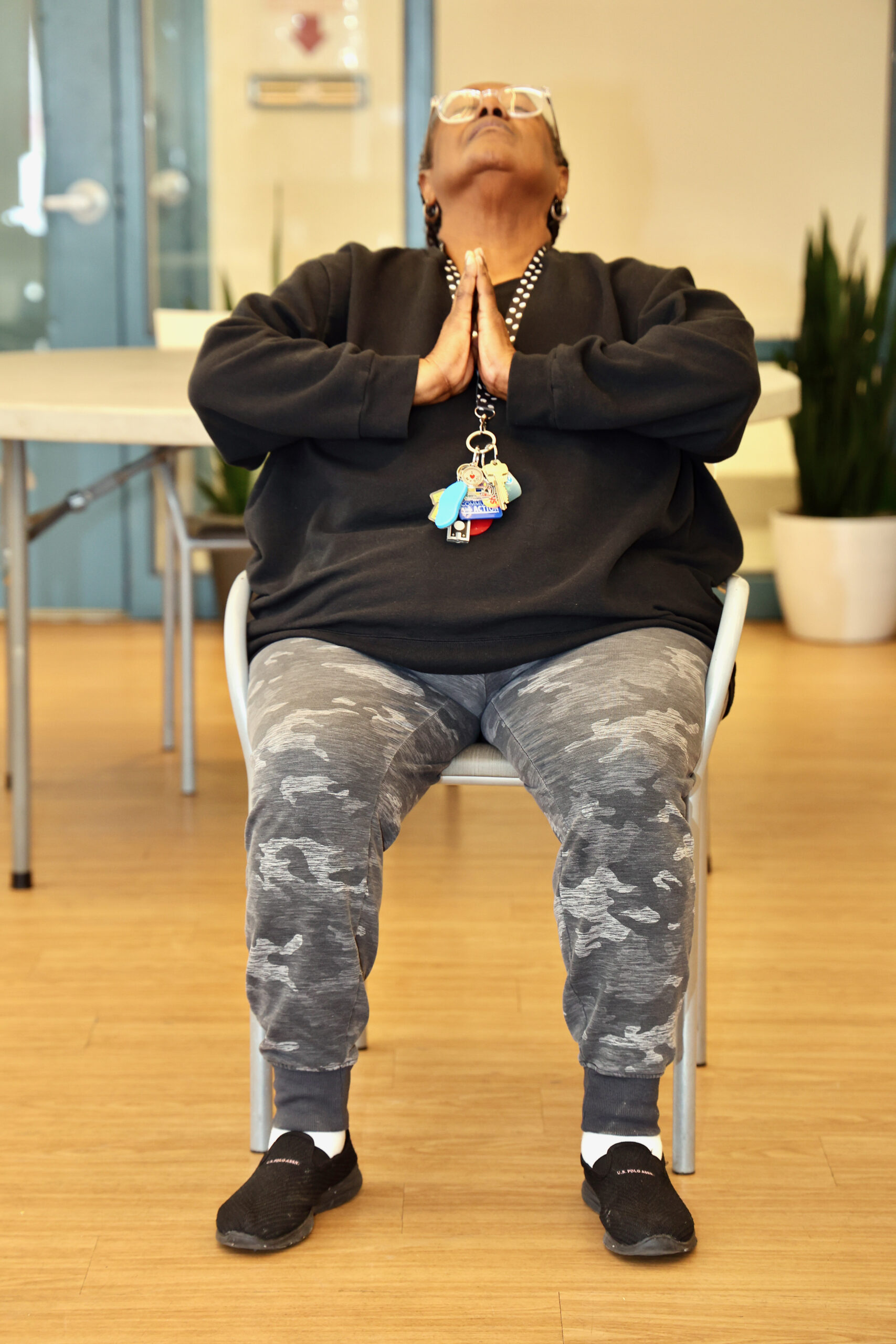 Senior participant practicing seated yoga with hands in prayer position at Grace Manor