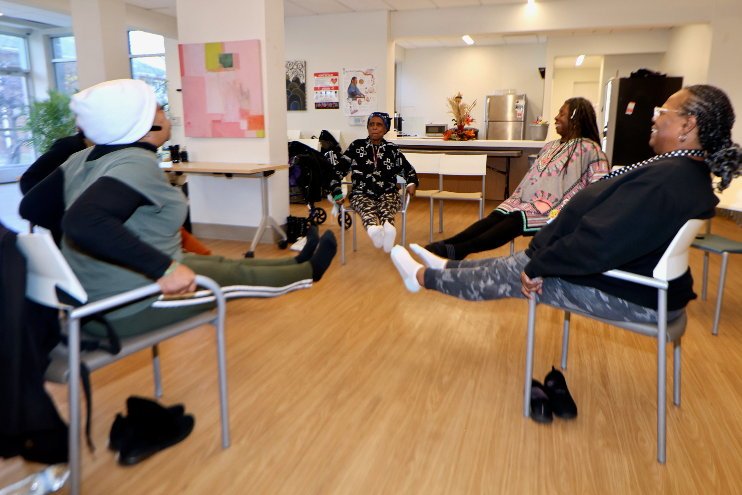 Seniors participating in a seated leg extension exercise during a yoga session at Grace Manor