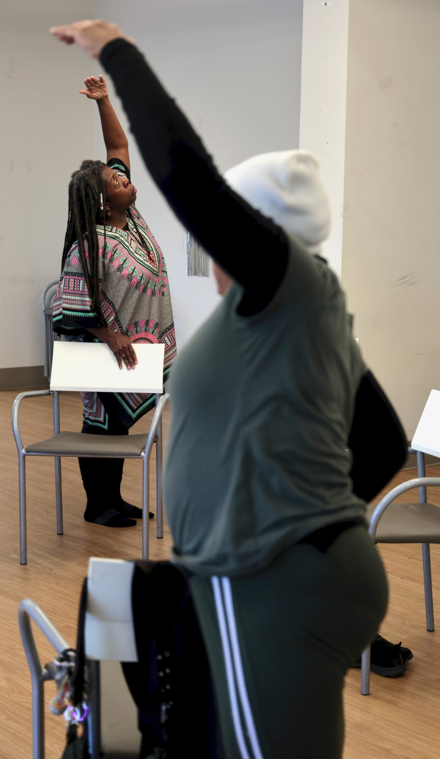 Yoga instructor guiding a standing stretch for seniors during a wellness session at Grace Manor