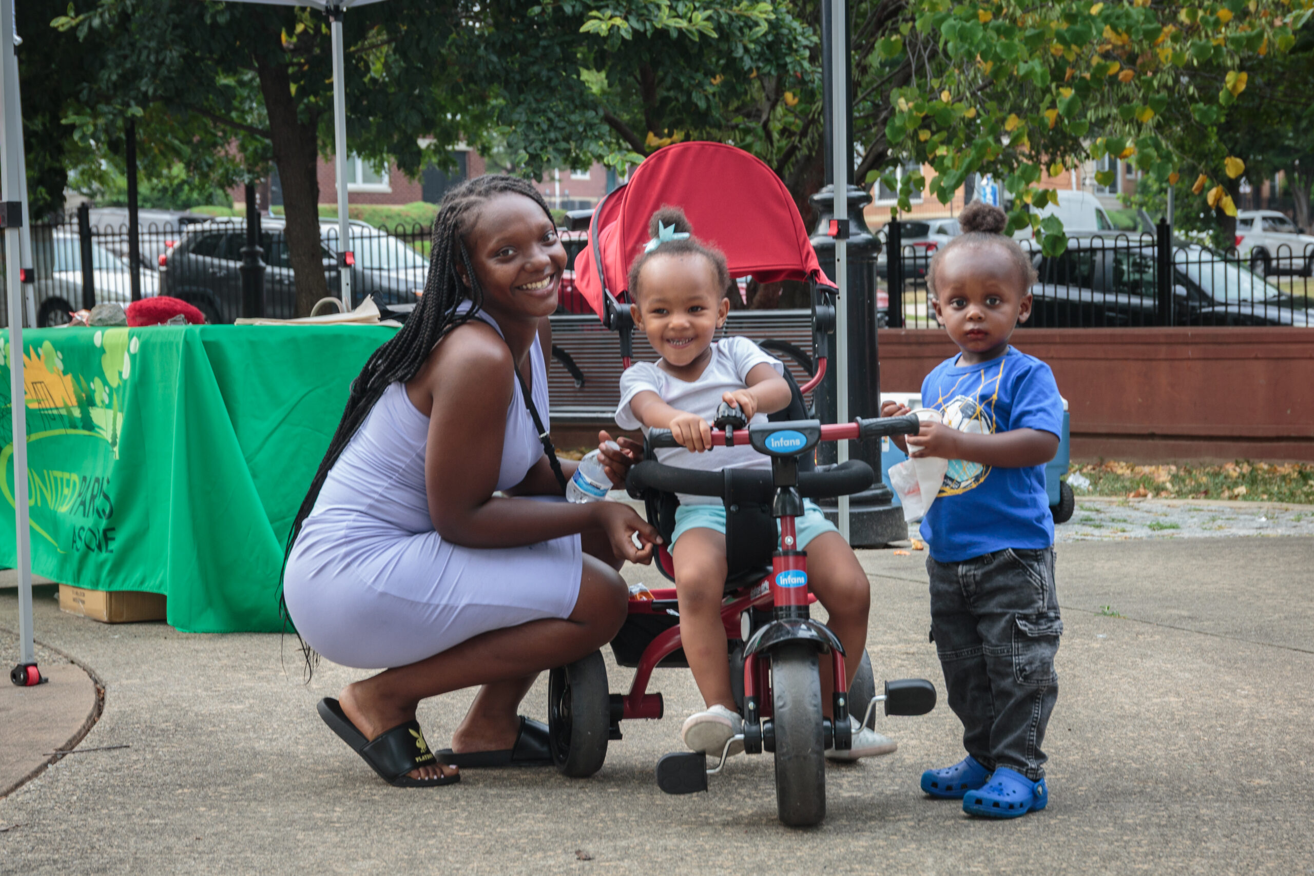 Parent and young children smiling near a stroller at Jesse Allen Park