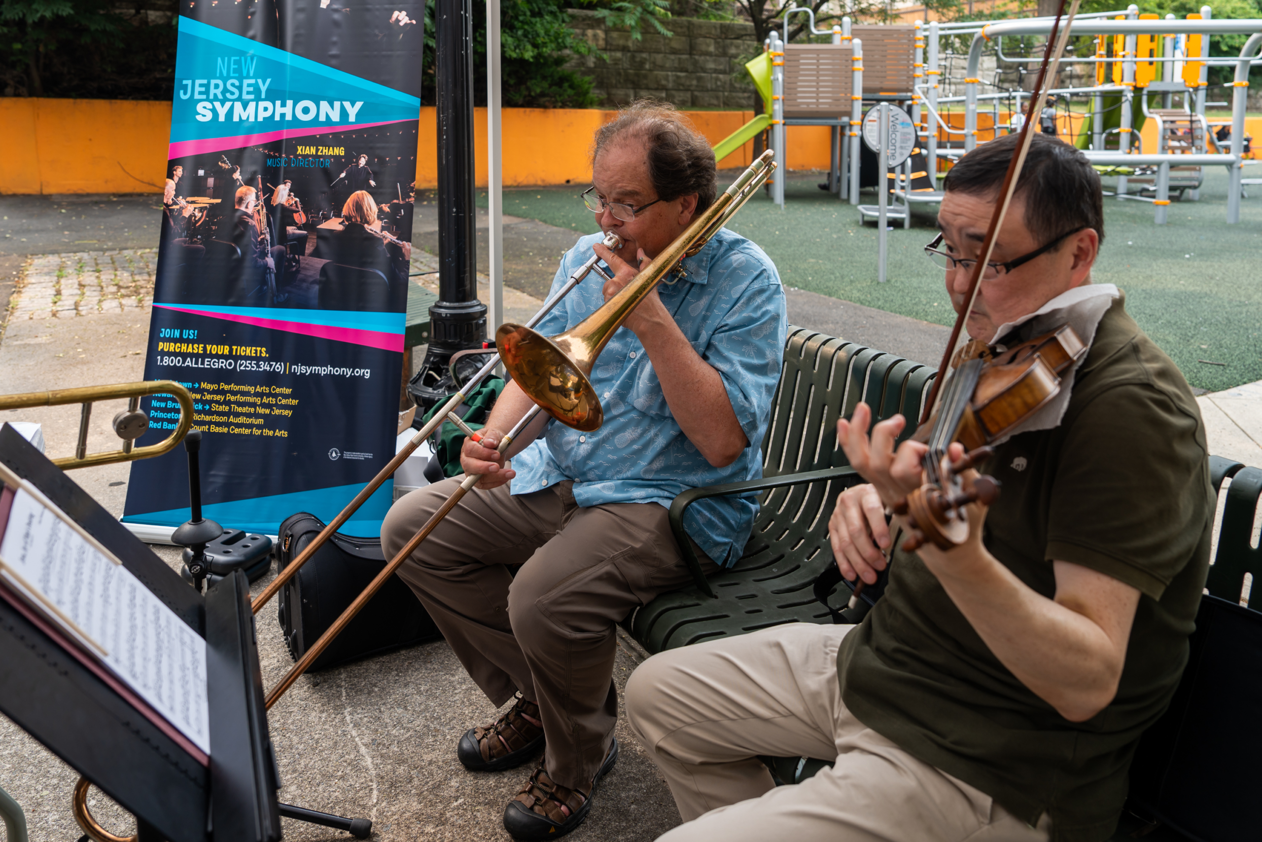 Live musicians performing trombone and violin during National Night Out at a Newark community park.