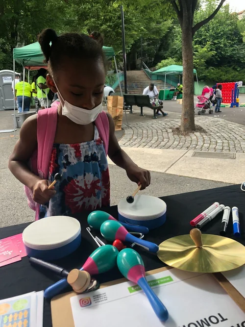 Child participating in music activities at Mildred Helms Park community event