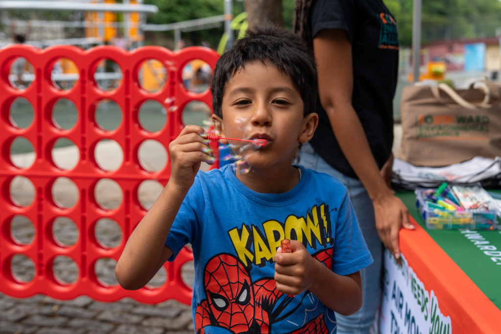 Child blowing bubbles at Mildred Helms Park during family community event