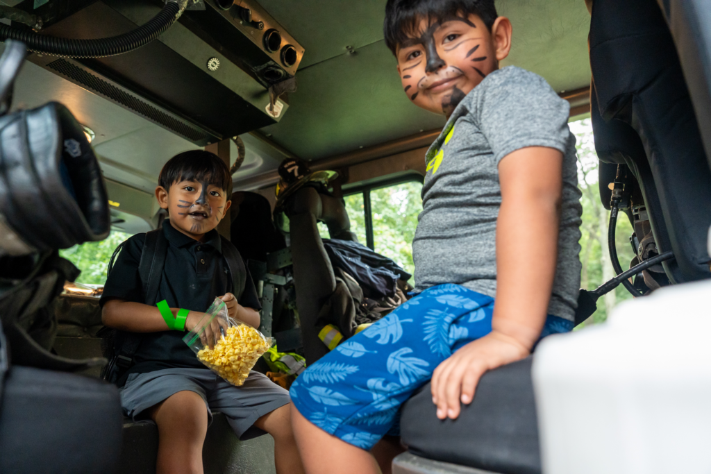 Children sitting inside a fire truck during a public safety activity at Mildred Helms Park