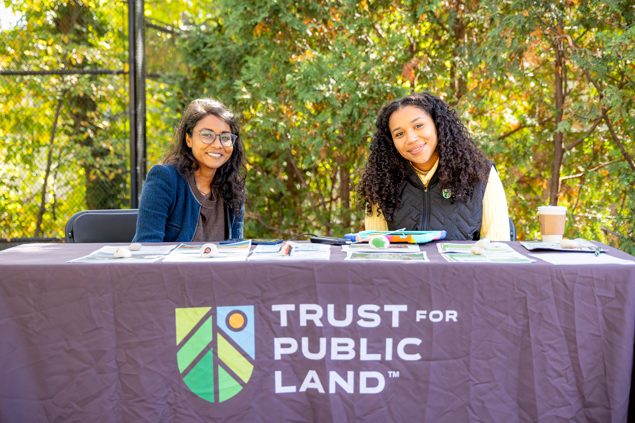 Two representatives from Trust for Public Land seated at a resource table during the community fair