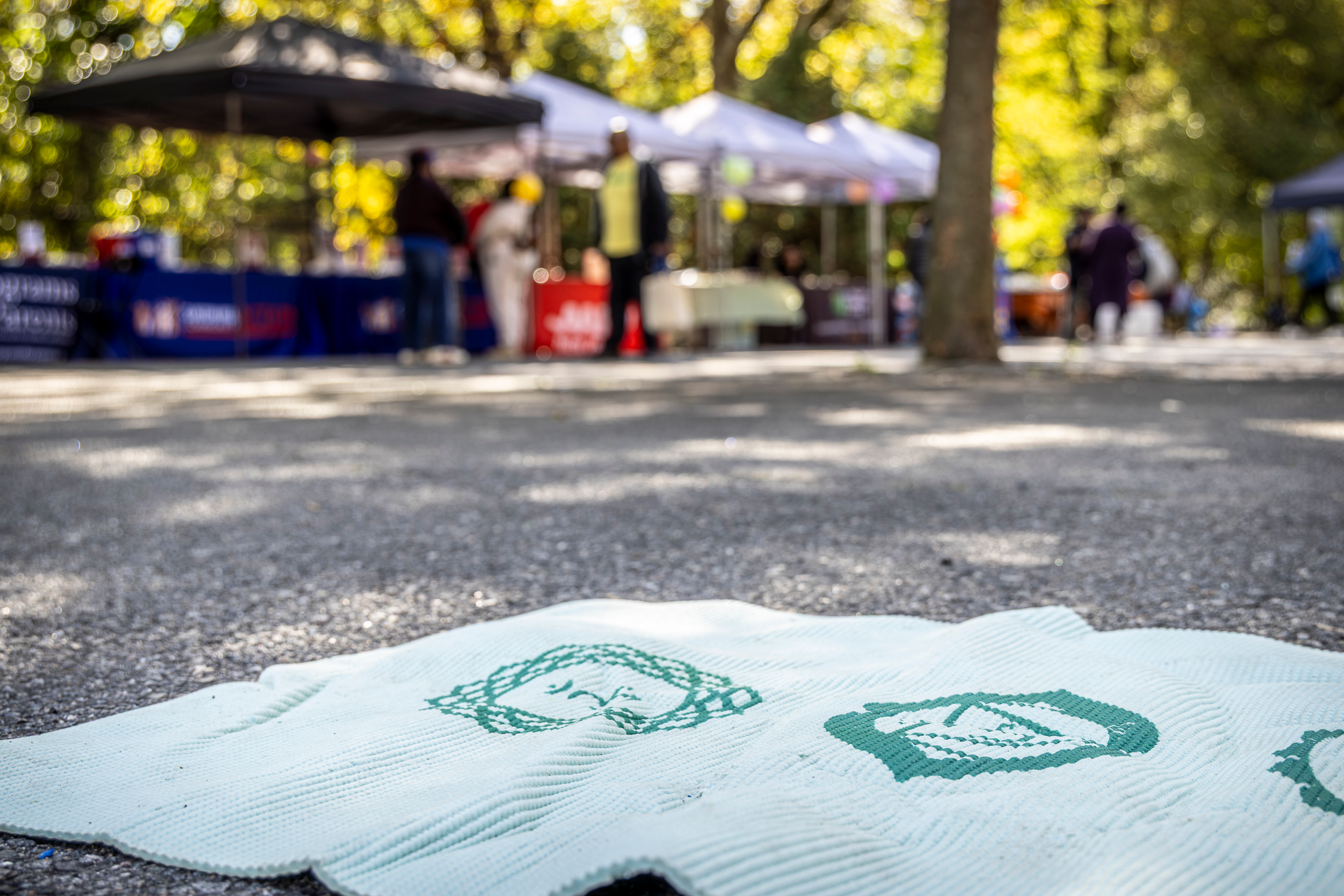 Close-up of a wellness mat in Mildred Helms Park with community tents blurred in the background.
