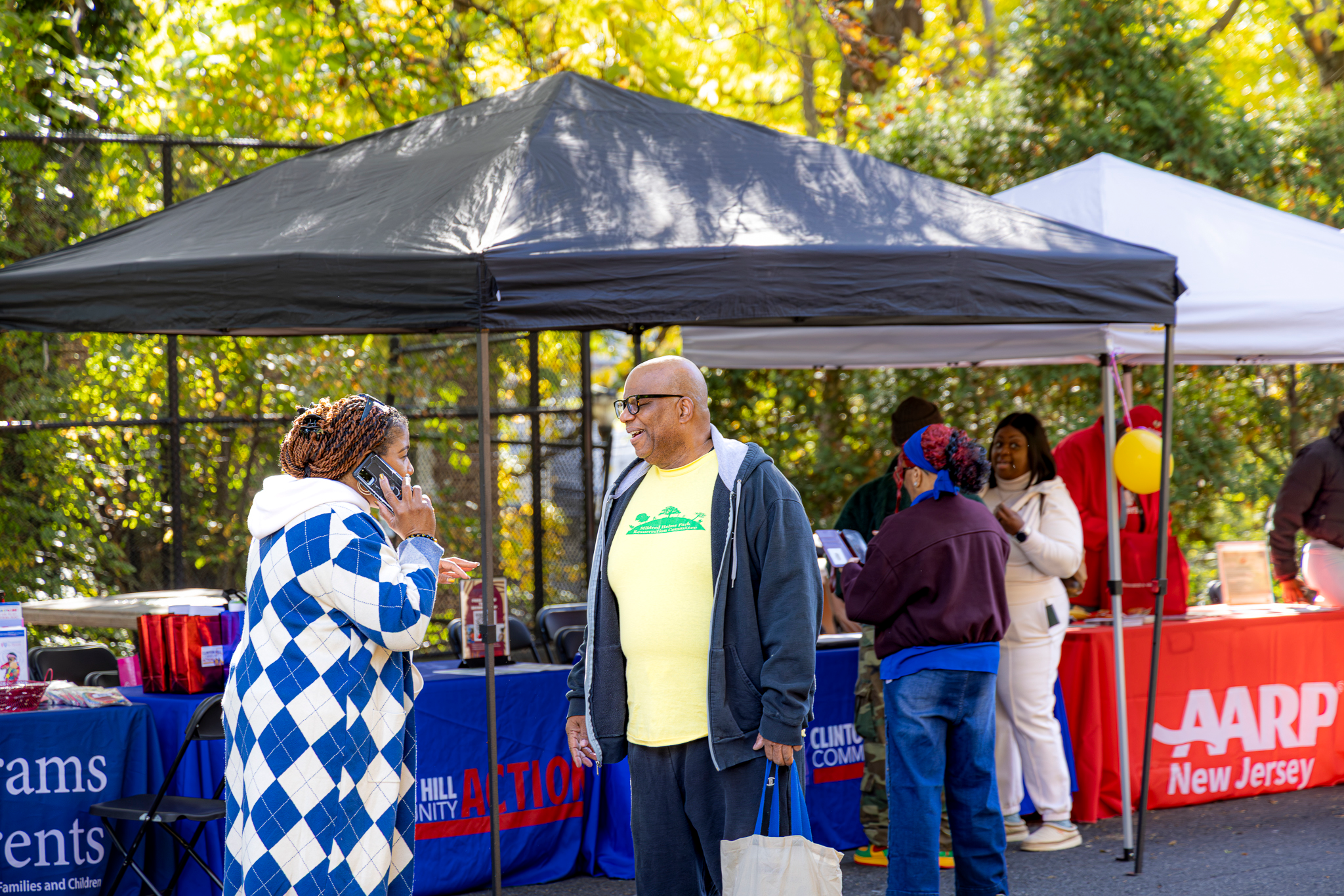 Community members speaking near multiple partner organization tables during the outdoor fair.